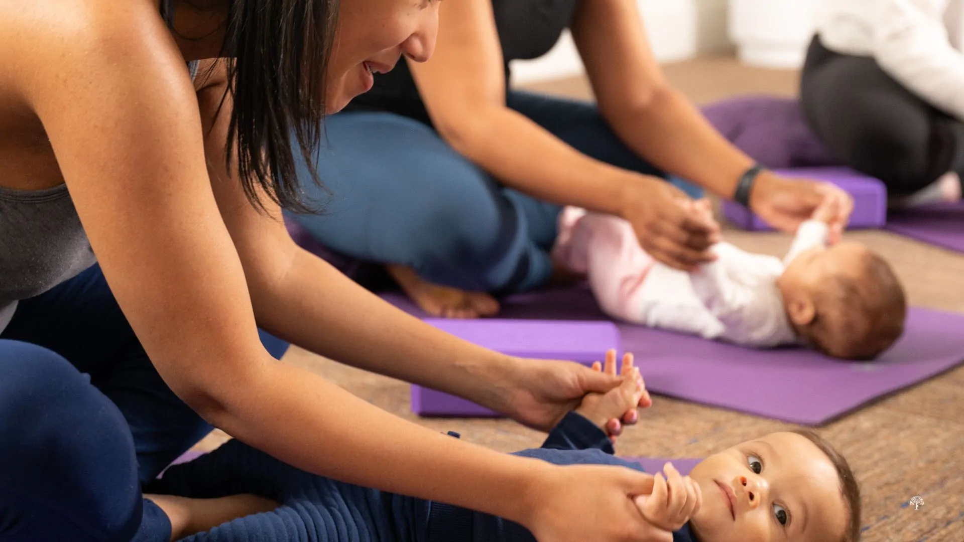 Close-up of mothers and babies practicing Mommy & Me yoga at Taylor Physical Therapy & Wellness in Winston-Salem, NC, focusing on gentle stretching and postpartum connection.